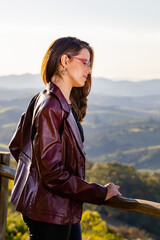 Young woman on a mountain gazebo looking at the landscape with hills and native vegetation and...