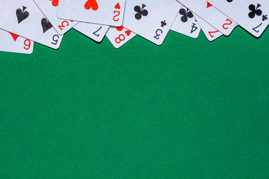 Playing cards on green felt casino table. Background with copy space in center