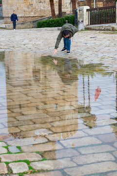 Chico joven realizando poses graciosas frente a un charco de agua situado frente a la Torre del Oro de Sevilla
