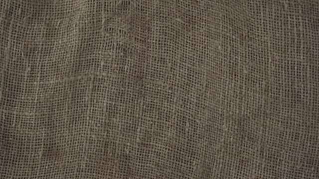 Rough agricultural bagging cloth rotate with slow speed top view. Background of textile and drap.