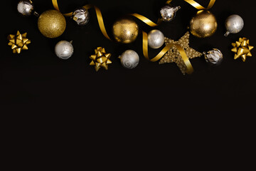 Fototapeta premium Christmas background with fir branches, gold decorations and pine cones on a black table. Flat lay. top view with copy space