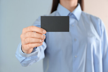 Woman holding blank business card on color background, closeup. Mockup for design