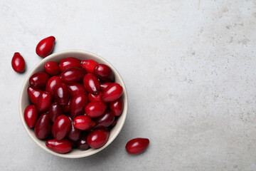 Fresh ripe dogwood berries in bowl on light grey table, flat lay. Space for text