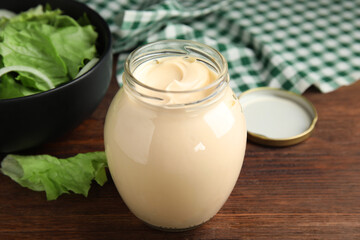 Jar of delicious mayonnaise and fresh salad on wooden table