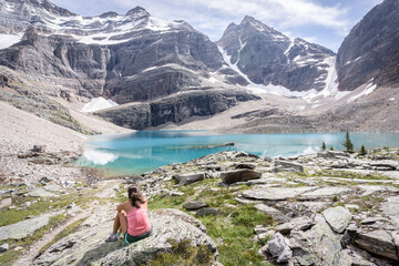 Fototapeta premium Female hiker sitting on the bank of turquoise glacier lake in beautiful alpine environment