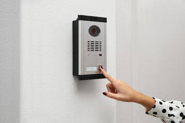 African-American woman ringing intercom with camera in entryway, closeup