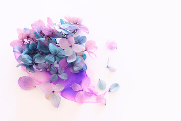 Creative image of pink and turquoise Hydrangea flowers on artistic ink background. Top view with...