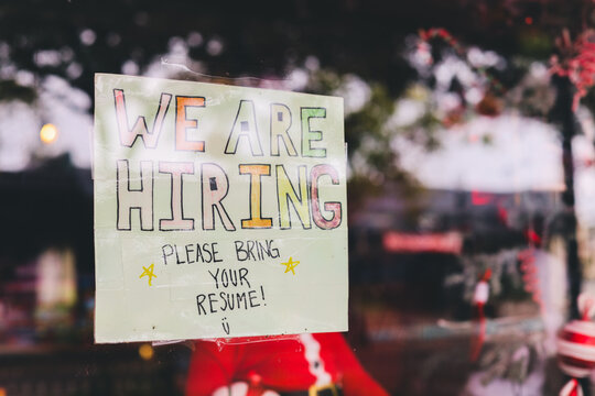 hand made we are hiring sign in a storefront window help wanted  stock photo 