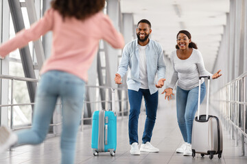 Happy black family meeting running kid in airport