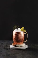 Traditional american alcoholic beverage moscow mule in copper mug with lemon and thyme on white...