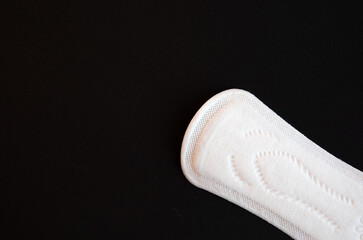 One Discrete Panty Liner or Pad for Woman on Black background. Daily Hygiene Products, Women's Pads for Every Day Hygiene Care. Copy space