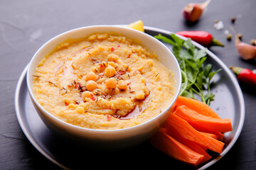 Hummus on a dark background. Hummus - boiled chickpea puree with the addition of spices and herbs, vegetable, tahini
