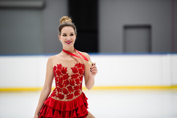 happy figure skater in red dress holding golden medal