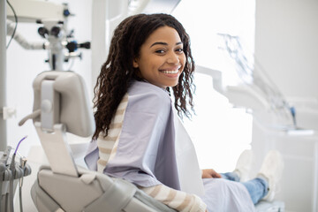 Happy Young Black Female Patient Sitting In Chair At Dental Clinic