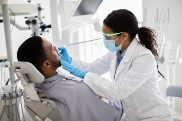 Fototapeta premium Portrait Of Black Male Patient Getting Teeth Treatment With Dentist At Clinic