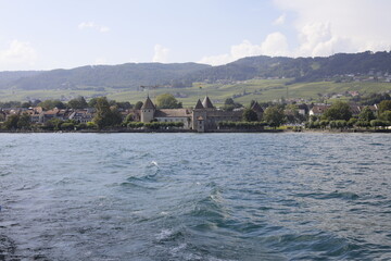 Fototapeta premium Chateau et maisons de Rolle avec le village de Mont-sur-Rolle vue depuis le lac Léman