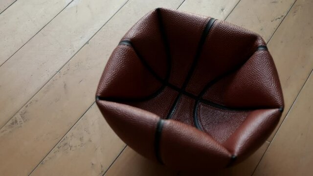 Close up deflated basketball on wooden floor.