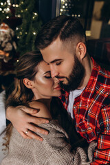 A guy with a girl is celebrating Christmas. A loving couple enjoys each other on New Year's Eve in a cozy home environment. New Year's love story. Close-up.