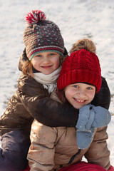 Fototapeta premium Winter children in snow backcground. Two winter girls hugging smiling. Winter girls portrait. 