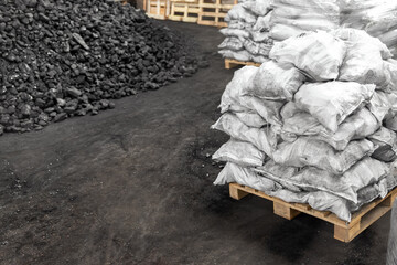 Big heap of dark black lump coal on floor bulk. Charcoal sorage at warehouse stock reserve....