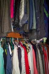 Lots of clothes on hangers, hanging in the closet. Wardrobe clutter. Sustainable life and smart consumption
