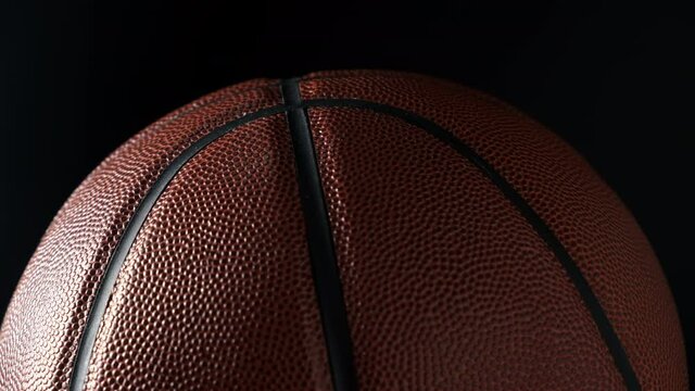 Close up shot of rotating basketball ball on dark black background. Basketball concept.