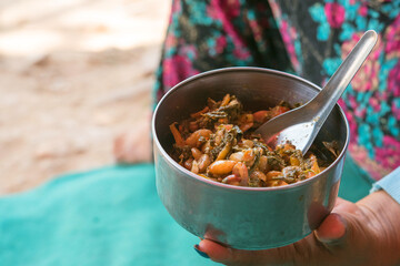 Hand holding bowl of Lahpet Thoke, Burmese tea leaf salad　ミャンマーの茶葉サラダ「ラペットゥ」