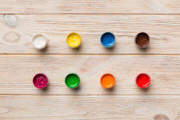 jars with gouache of different colors on Colored background. hobby painting. Top view with empty space. workplace for creativity. home teaching concept drawing
