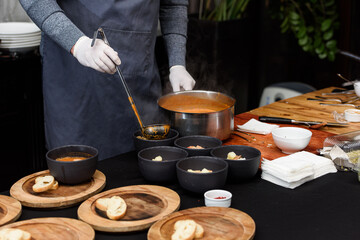 cooking process of Suquet de Peix soup with potatoes, herbs and fish with the addition of picada close-up in a saucepan on the table.