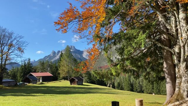 Beautiful autumn landscape in the near of Scharnitz in Austria with a cabin colorful trees and high Karwendel mountains in the background