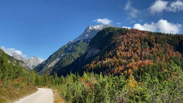 Beautiful autumn landscape in the near of Scharnitz in Austria with colorful deciduous trees and snow covered mountains in the background, panning panorama shot