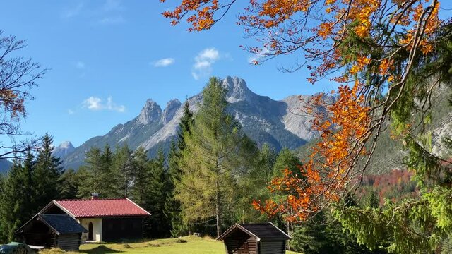 Beautiful autumn landscape in the near of Scharnitz in Austria with a cabin colorful trees and high Karwendel mountains in the background, tilt shot close up