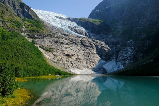 Boyabreen Glacier and a glacial lake  Jostedalsbreen National Park  in Norway. A small tent stands at the foot of the glacier.