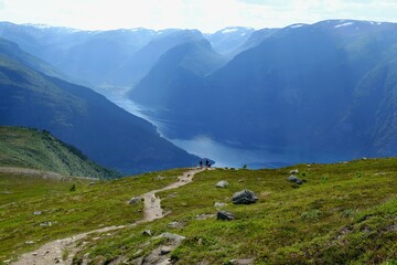 Amazing scenery of viewpoint on Priest Røyrgrind mountain. There is amazing view of Aurlandsfjord, one of most beautiful fjords in Norway. Silhouettes of two people on path.