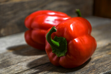Two red bell peppers lie on a wooden table.