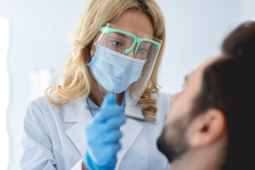 Female dentist in face mask and protective glasses making treatment