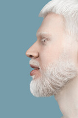 Obraz premium Closeup profile portrait of albino man with white hair, beard, eyelashes and brows, turquoise background, side view