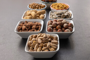 Pistachio in selective focus. Background of dried mulberry, hazelnut, pistachio, grape, almond, yellow chickpea and sunflower seeds.