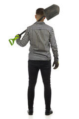 Man in lumberjack shirt is standing with spade on his shoulder. Rear view. Studio shot.