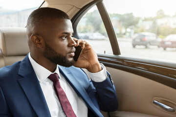 Concentrated black businessman going to business meeting, having phone conversation