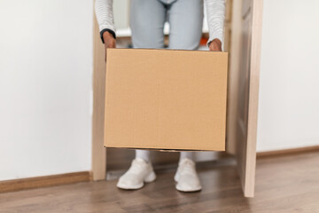 Unrecognizable African American Lady Taking Delivered Box From Floor Indoor