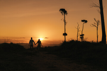 Fototapeta na wymiar silhouette of a couple walking on the montains at sunset