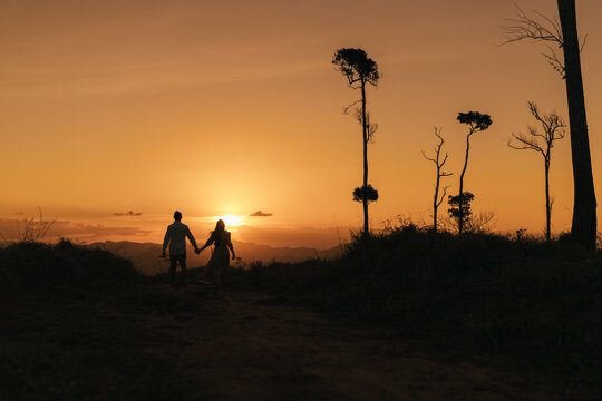 silhouette of a couple walking on the montains at sunset