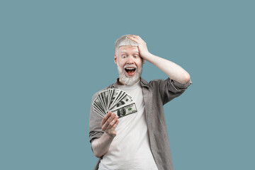 Excited extraordinary albino guy holding lots of money, touching head with shocked emotion over...