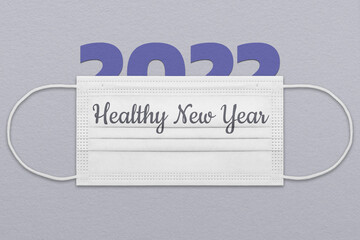 New Year's postcard with a face mask in trendy colors of 2022 with the inscription Healthy New Year. The concept of a safe holiday.