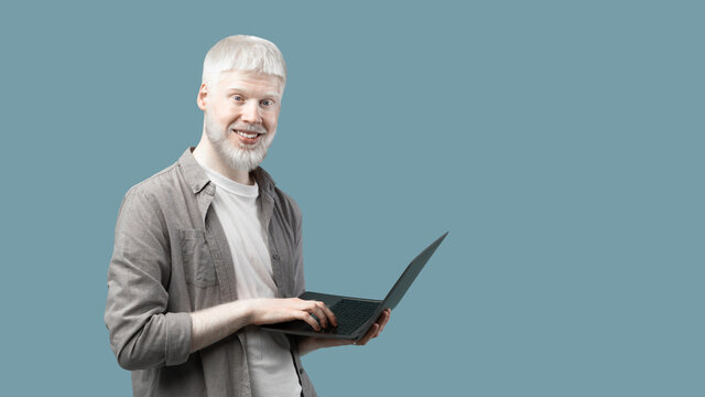 Remote job for students. Excited extraordinary guy with laptop computer standing over blue background with copy space