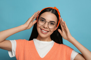 Young woman wearing stylish bandana on light blue background