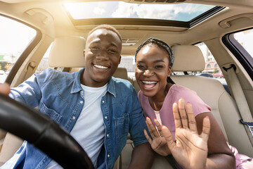 Joyful african american couple taking selfie while having car trip