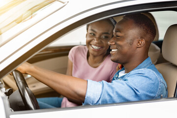 Cheerful black couple sitting in car together