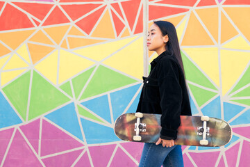 young woman walks with a skateboard in her hand